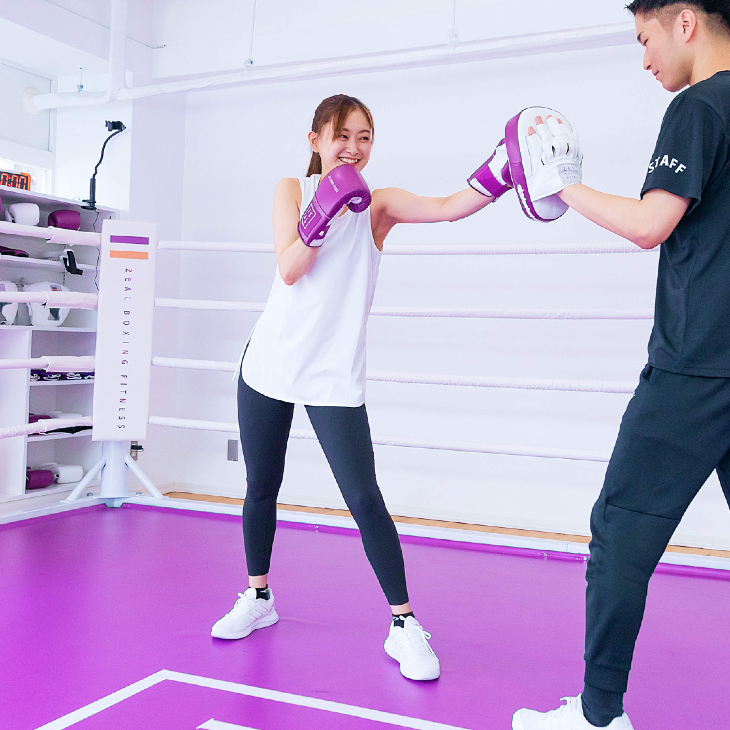 ボクシングをする女性とミットを持つインストラクターの男性